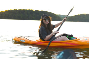 Girl wearing NÖZ sunscreen in a raft with the trees in the background holding a row.